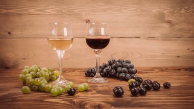 Kırmızı ve beyaz şarap, gözlük ve ahşap masa üzüm