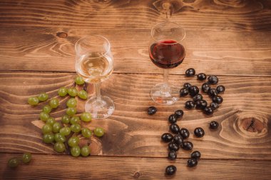Kırmızı ve beyaz şarap, gözlük ve ahşap masa üzüm