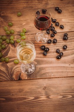 Kırmızı ve beyaz şarap, gözlük ve ahşap masa üzüm