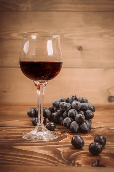 Copa de vino tinto y uvas sobre mesa de madera rústica —  Fotos de Stock