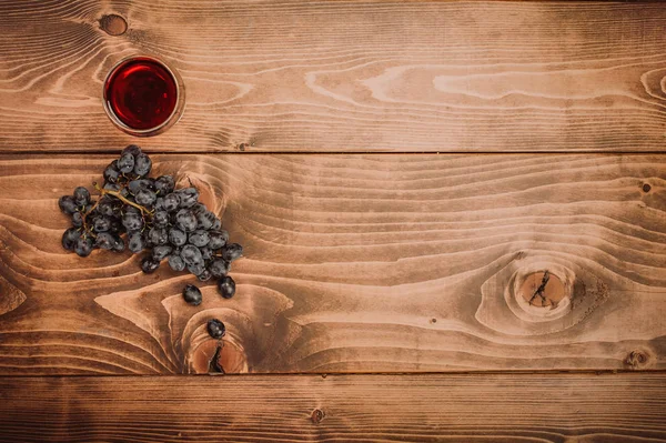 Copa de vino tinto y uvas sobre mesa de madera rústica —  Fotos de Stock