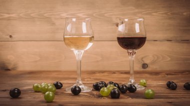Kırmızı ve beyaz şarap, gözlük ve ahşap masa üzüm