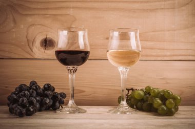 Kırmızı ve beyaz şarap, gözlük ve ahşap masa üzüm