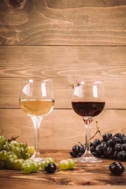Kırmızı ve beyaz şarap, gözlük ve ahşap masa üzüm