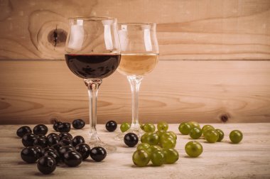 Kırmızı ve beyaz şarap, gözlük ve ahşap masa üzüm