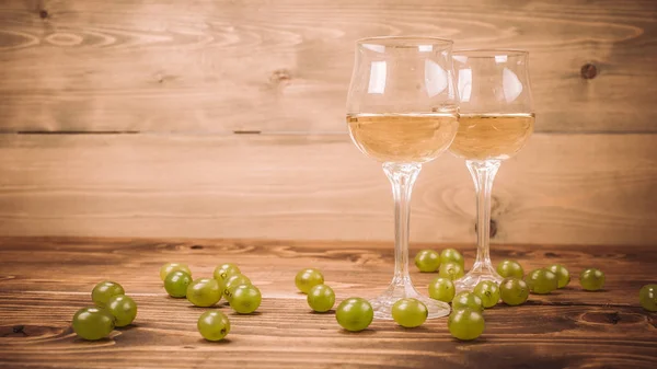 Два бокала белого вина и винограда на деревянном столе — стоковое фото