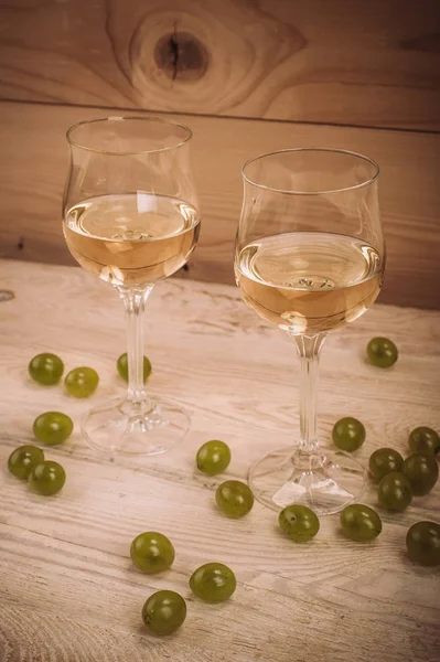 İki kadeh beyaz şarap ve üzüm ahşap tablo