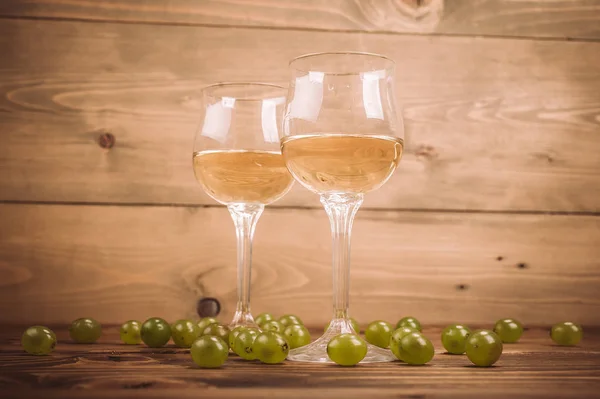 Dos copas de vino blanco y uvas sobre mesa de madera —  Fotos de Stock