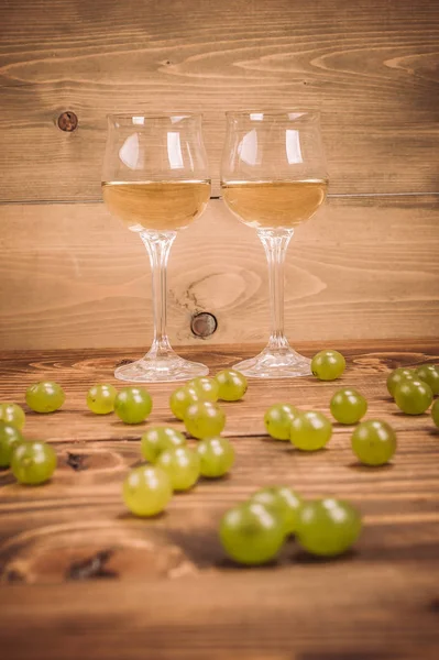 Dos copas de vino blanco y uvas sobre mesa de madera —  Fotos de Stock
