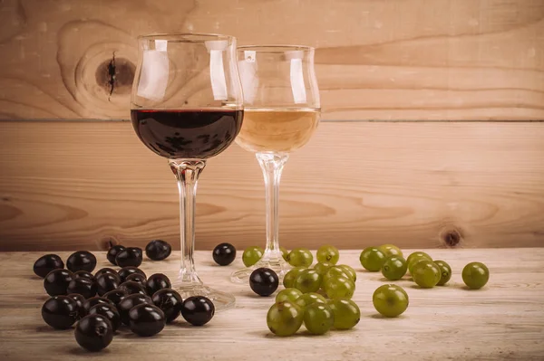 Kırmızı ve beyaz şarap, gözlük ve ahşap masa üzüm