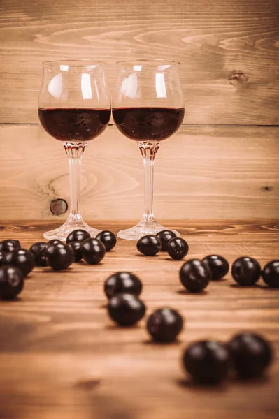 Two glasses of red wine and grapes on wooden table — Stock Photo, Image