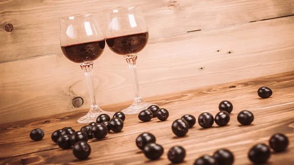 İki kadeh kırmızı şarap ve üzüm ahşap tablo