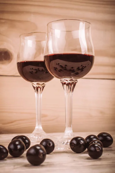 Dois copos de vinho tinto e uvas na mesa de madeira — Fotografia de Stock