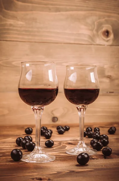 İki kadeh kırmızı şarap ve üzüm ahşap tablo