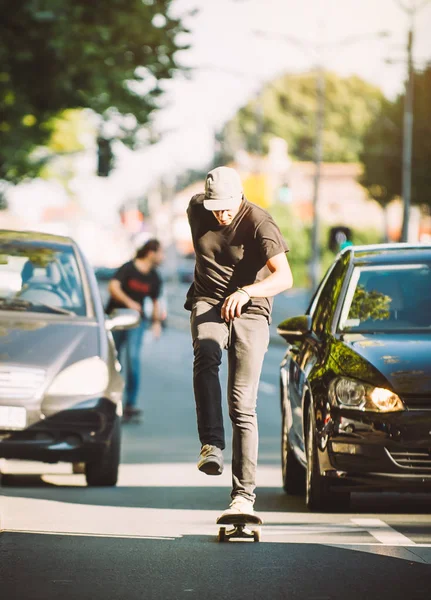 Two pro skateboard rider ride skate through cars on street — Stock Photo, Image