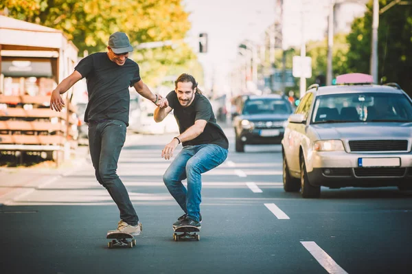 İki pro kaykay binici ride skate arabasının camından Caddesi üzerinde