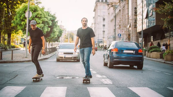 İki pro kaykay binici ride skate arabasının camından Caddesi üzerinde
