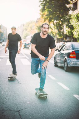 İki pro kaykay binici ride skate arabasının camından Caddesi üzerinde