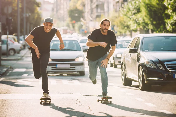 İki pro kaykay binici ride skate arabasının camından Caddesi üzerinde