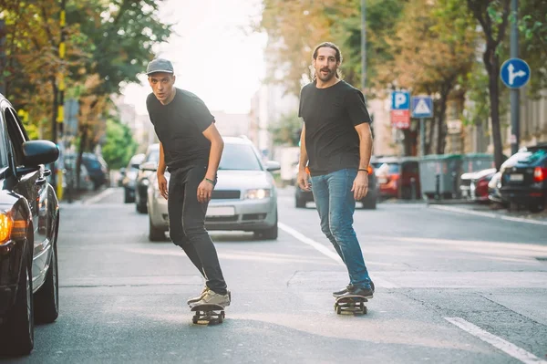 Due professionisti skateboard cavalcare pattinare attraverso le auto sulla strada — Foto Stock