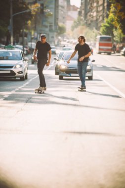 İki pro kaykay binici ride skate arabasının camından Caddesi üzerinde