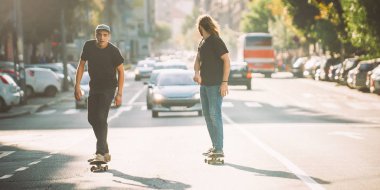 İki pro kaykay binici ride skate arabasının camından Caddesi üzerinde