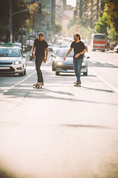 Deux pro skateboard rider patiner à travers les voitures dans la rue — Photo