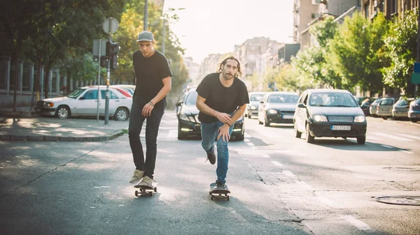 İki pro kaykay binici ride skate arabasının camından Caddesi üzerinde