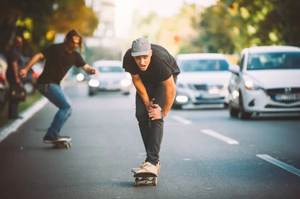 Due professionisti skateboard cavalcare pattinare attraverso le auto sulla strada — Foto Stock