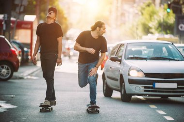 İki pro kaykay binici ride skate arabasının camından Caddesi üzerinde