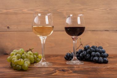 Kırmızı ve beyaz şarap, gözlük ve ahşap masa üzüm