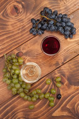 Kırmızı ve beyaz şarap, gözlük ve ahşap masa üzüm