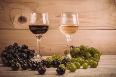 Kırmızı ve beyaz şarap, gözlük ve ahşap masa üzüm