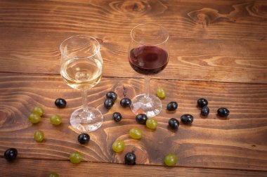 Kırmızı ve beyaz şarap, gözlük ve ahşap masa üzüm