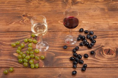 Kırmızı ve beyaz şarap, gözlük ve ahşap masa üzüm