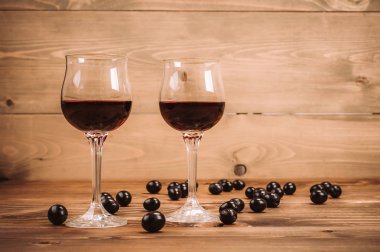 İki kadeh kırmızı şarap ve üzüm ahşap tablo