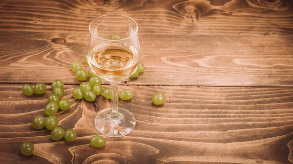 Стакан белого вина и винограда на деревенском деревянном столе — стоковое фото