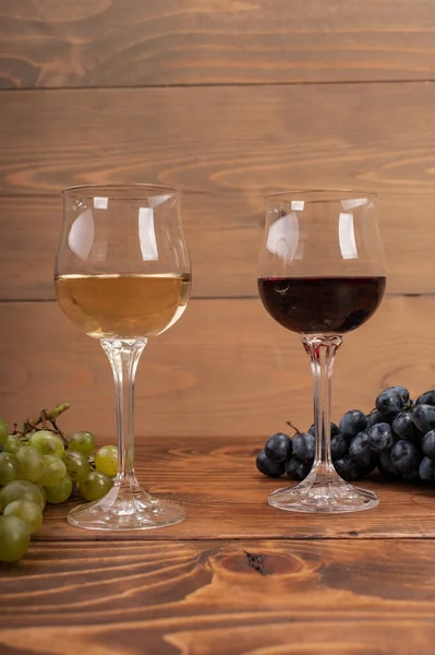 Kırmızı ve beyaz şarap, gözlük ve ahşap masa üzüm
