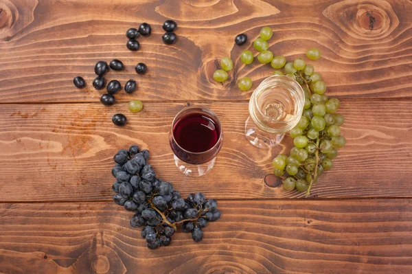 Copas de vino tinto y blanco y uva sobre mesa de madera —  Fotos de Stock