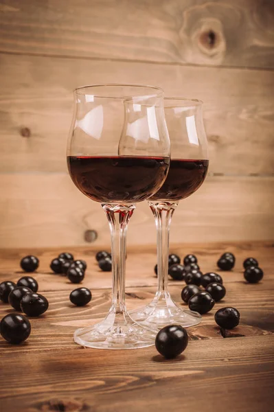 Dois copos de vinho tinto e uvas na mesa de madeira — Fotografia de Stock