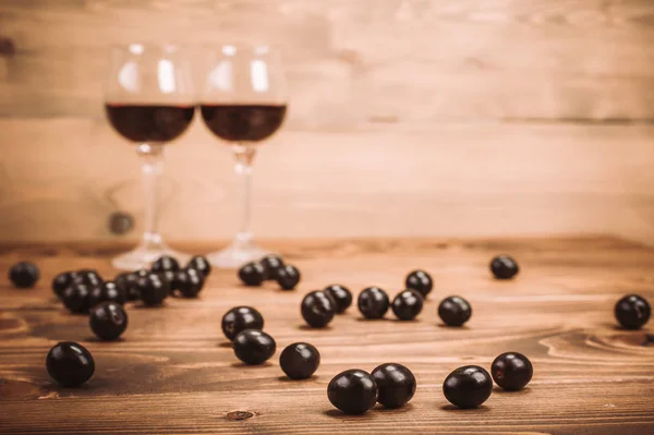 Dwie szklanki czerwonego wina i winogron na drewnianym stole — Zdjęcie stockowe