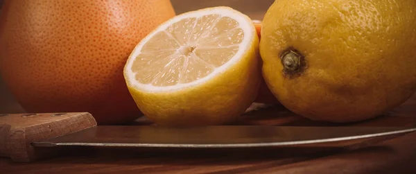 Plátky čerstvých organických citrusů s nožem na dřevěné desce — Stock fotografie