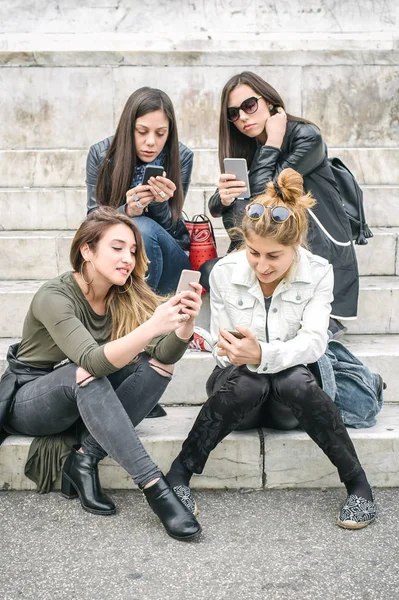 Négy lány meg boldog néz internet szociális média smartp — Stock Fotó