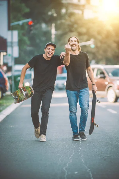 Δύο pro skateboard αναβάτη περπατώντας στους δρόμους κρατώντας τους skateboards — Φωτογραφία Αρχείου