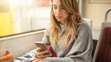 Genç kız bir cep telefonu şehir otobüs kullanır.