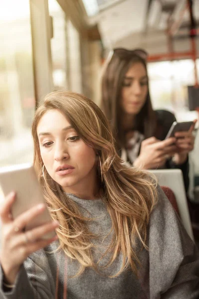 Chica joven utiliza un teléfono móvil en el autobús de la ciudad —  Fotos de Stock