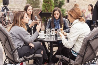 Sosyal ağ oynarken app smartphone kullanarak kafede dört kadın