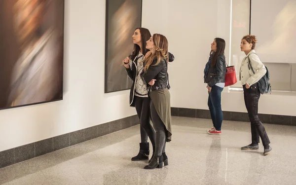Vier vriendinnen kijken naar moderne schilderkunst in art gallery and Museum — Stockfoto