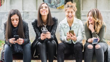 Bankta cep telefonu kullanarak mutlu dört arkadaş