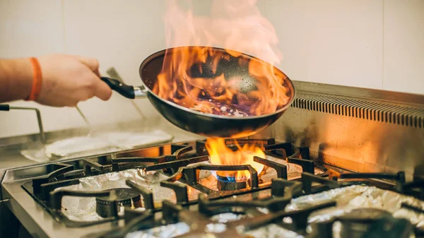 Chef cocinero prepara la comida en llama fuego quemar sartén — Foto de Stock